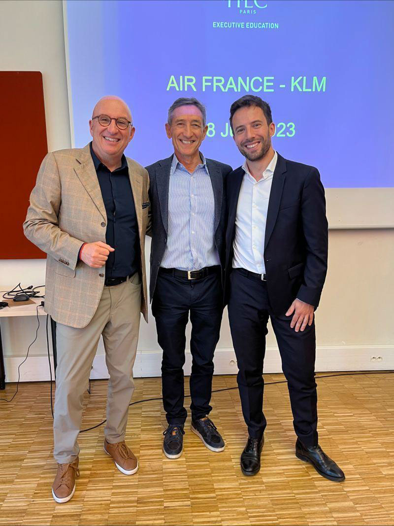 three men posing together in a classroom or conference room setting, with "HEC Paris Executive Education" and "Air France - KLM" branding visible in the background.