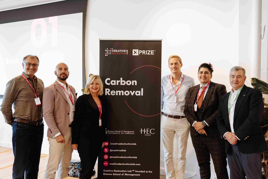 Group photo of six people standing next to a 'Carbon Removal' banner at a Creative Destruction Lab XPRIZE event. The individuals are smiling and wearing business attire with name badges. The banner includes logos from the Rotman School of Management at the University of Toronto and HEC Paris.