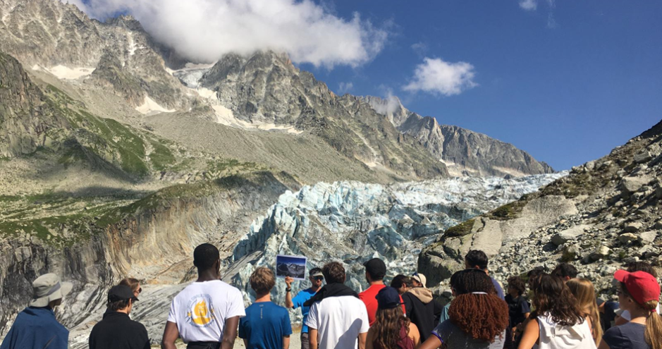 un groupe de jeunes ecoute un scientifique face au glacier de l'Argentière dans les montagnes de Chamonix